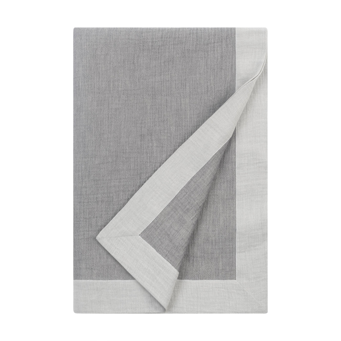 Corner fold detail revealing silver-grey linen throw's ivory reverse and border contrast.
