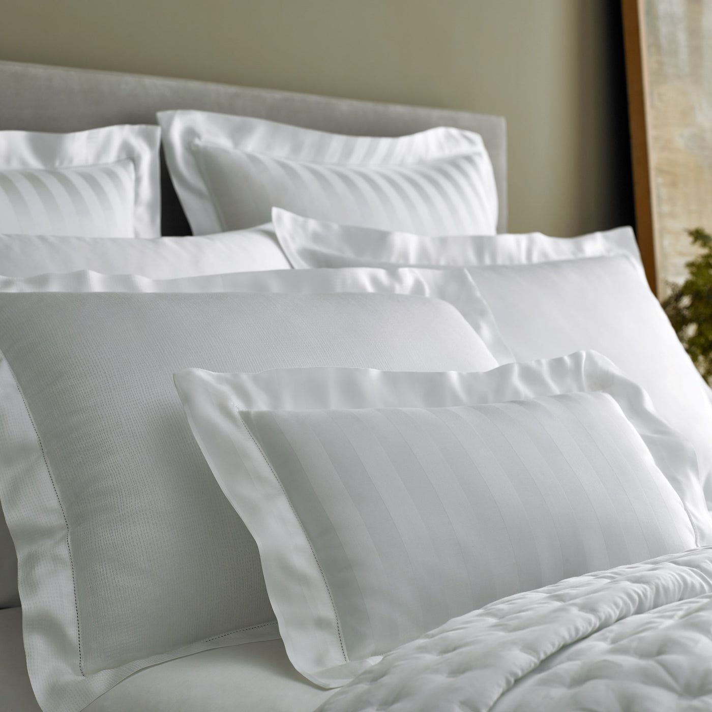 Close-up of white Athens bedding with subtle woven stripe texture on layered pillows.