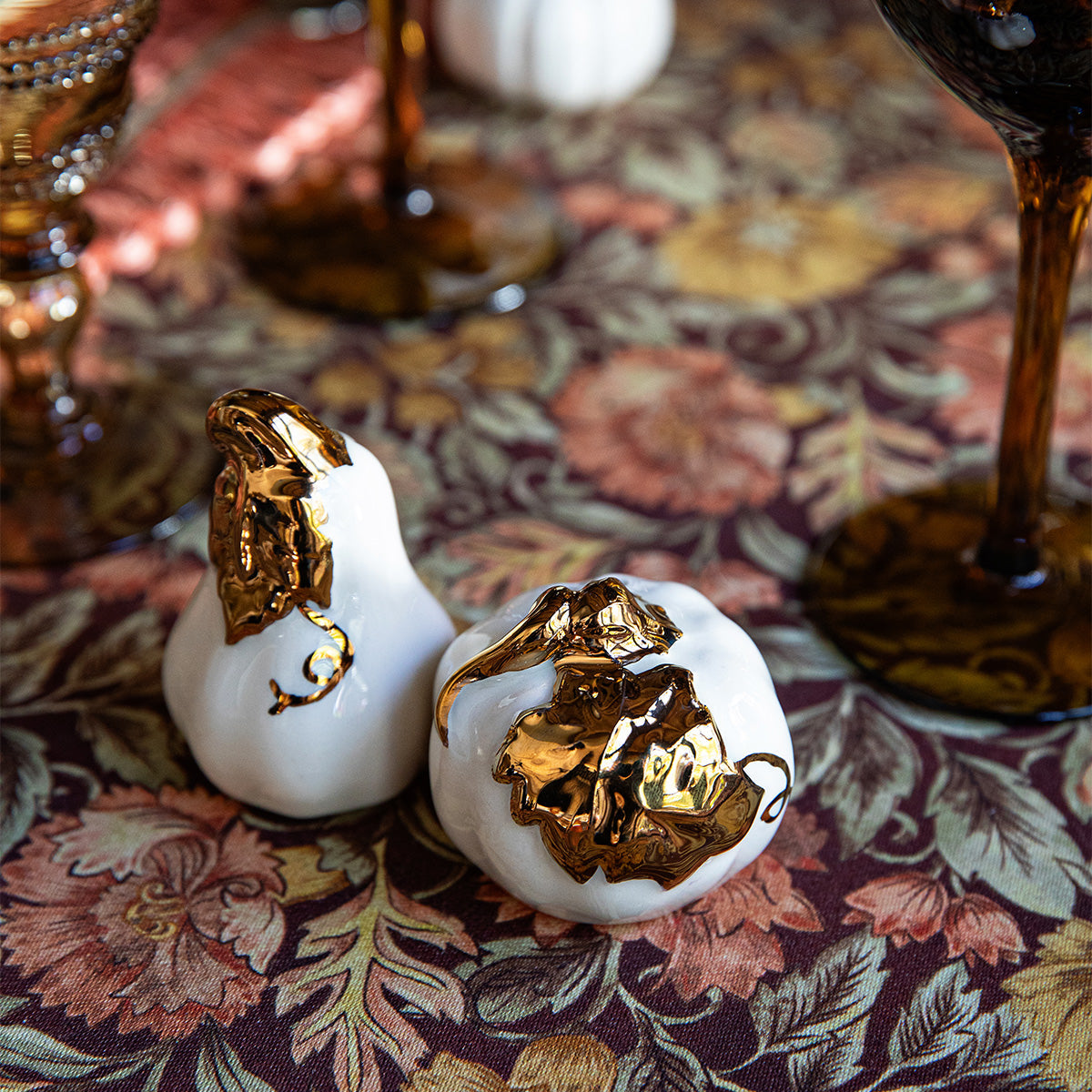 White and gold Forest Walk pumpkin and gourd salt and pepper shakers on a floral tablecloth