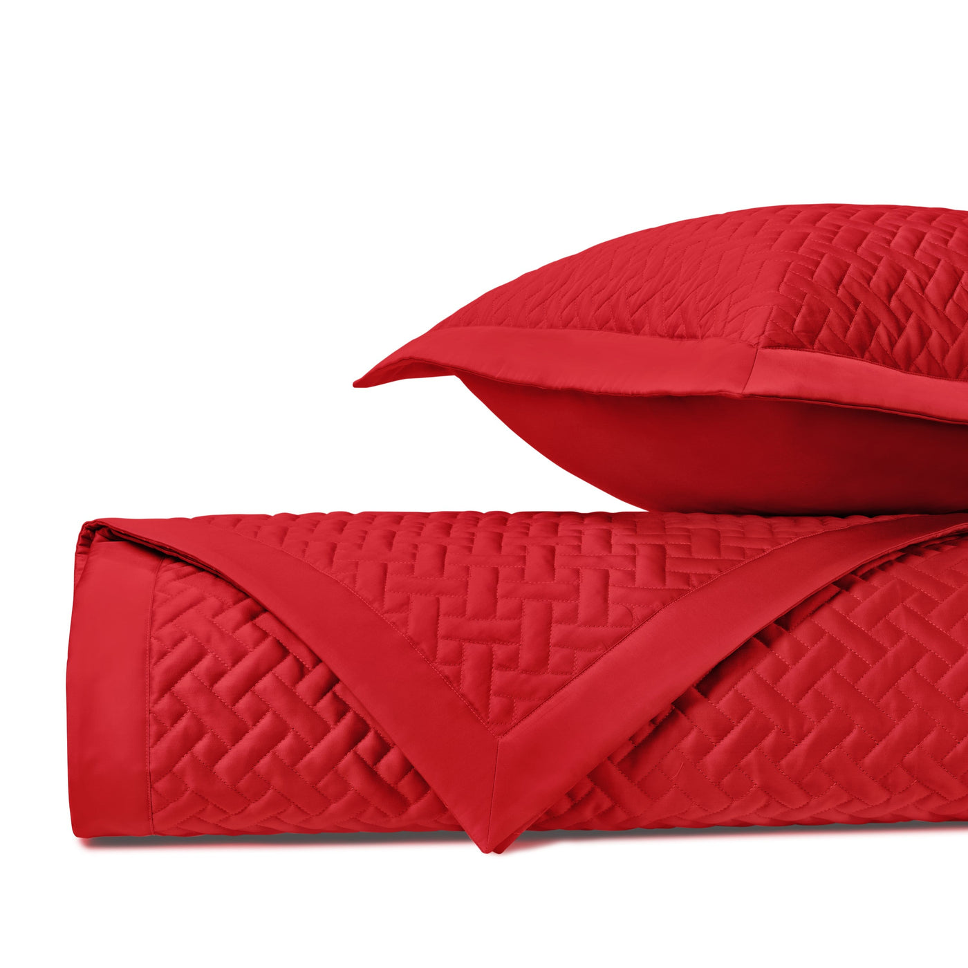 Close-up of crimson quilted basketweave texture on rolled coverlet with sham.