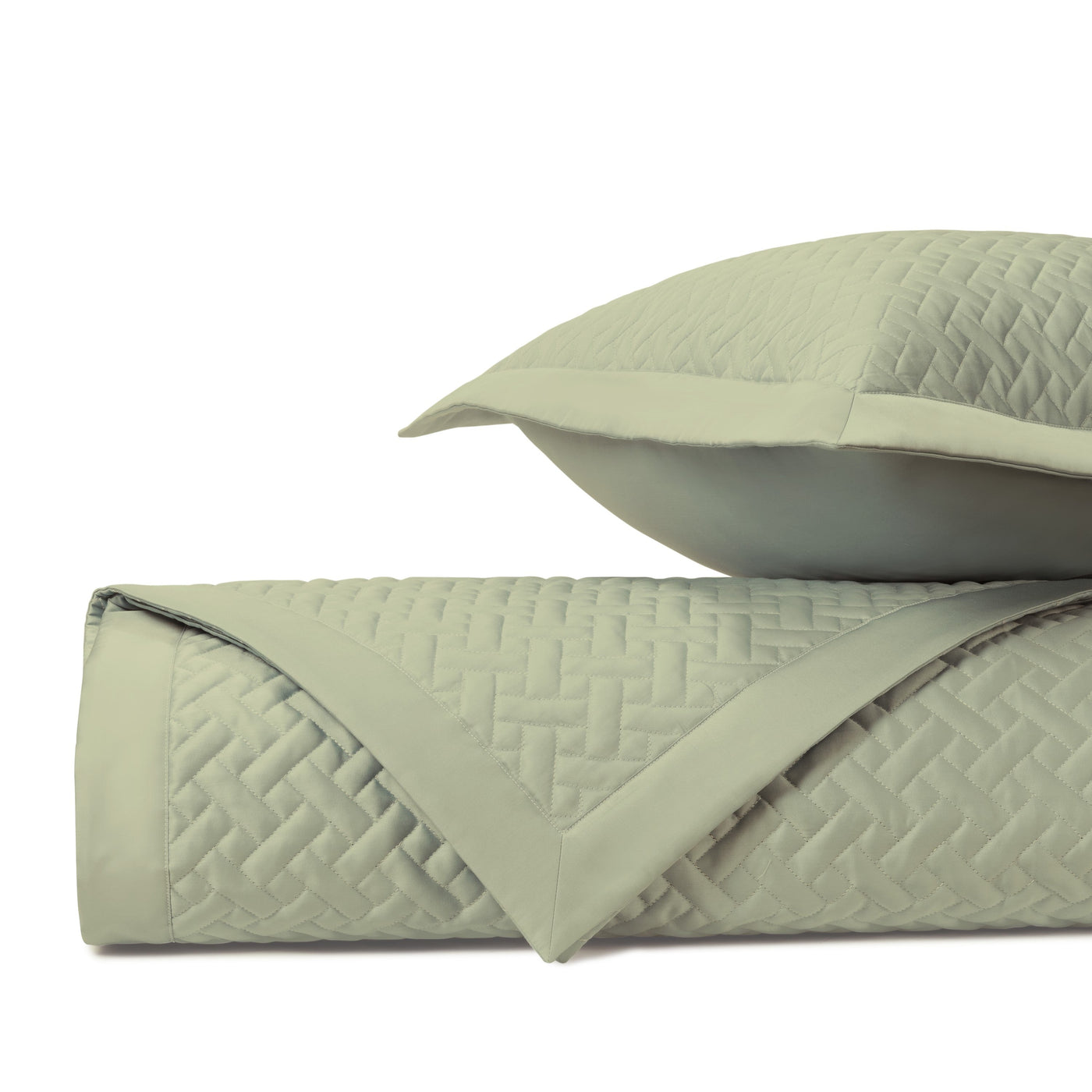 Close-up of sage green quilted basketweave texture on folded coverlet and sham.