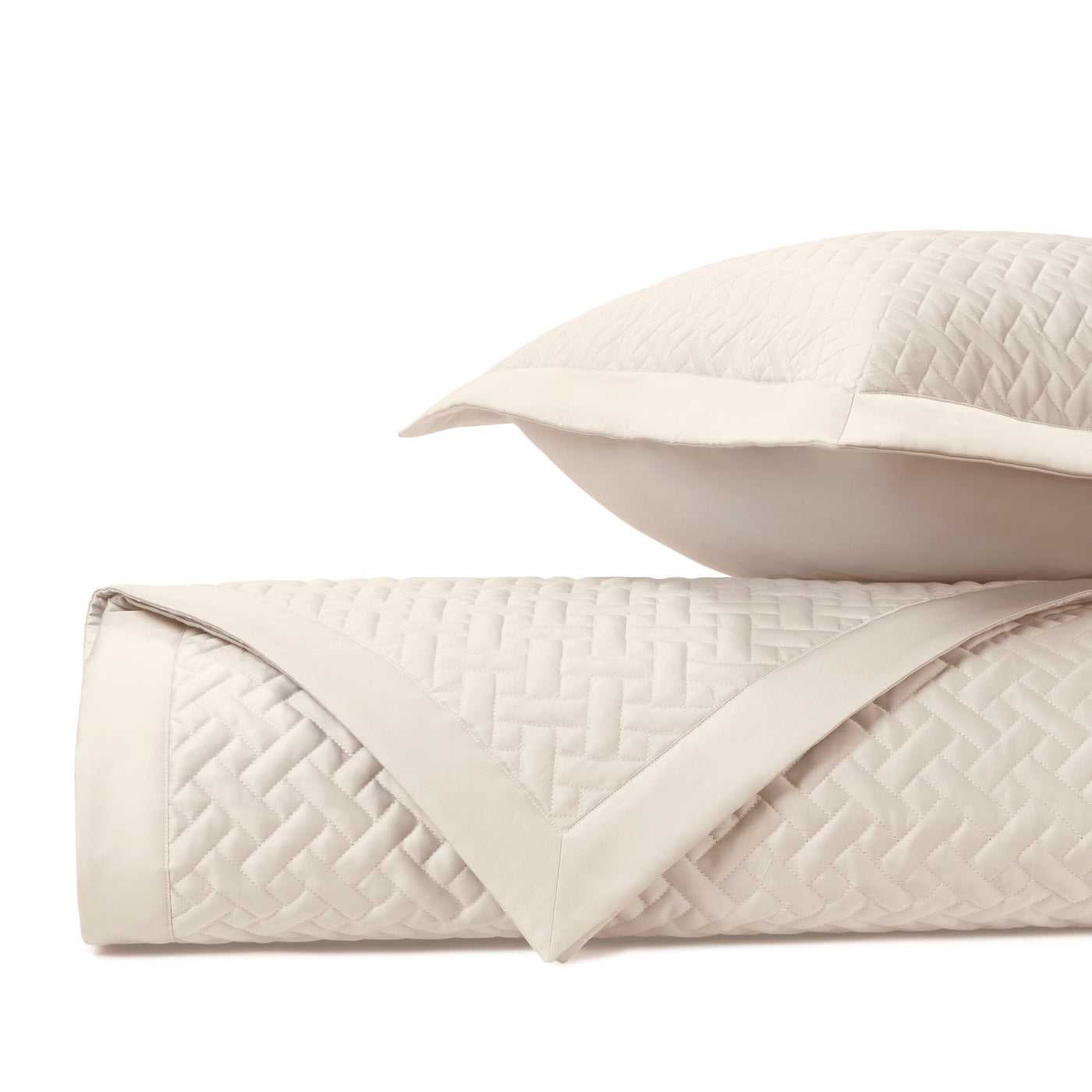 Close-up of ivory quilted basketweave texture on folded coverlet and sham.
