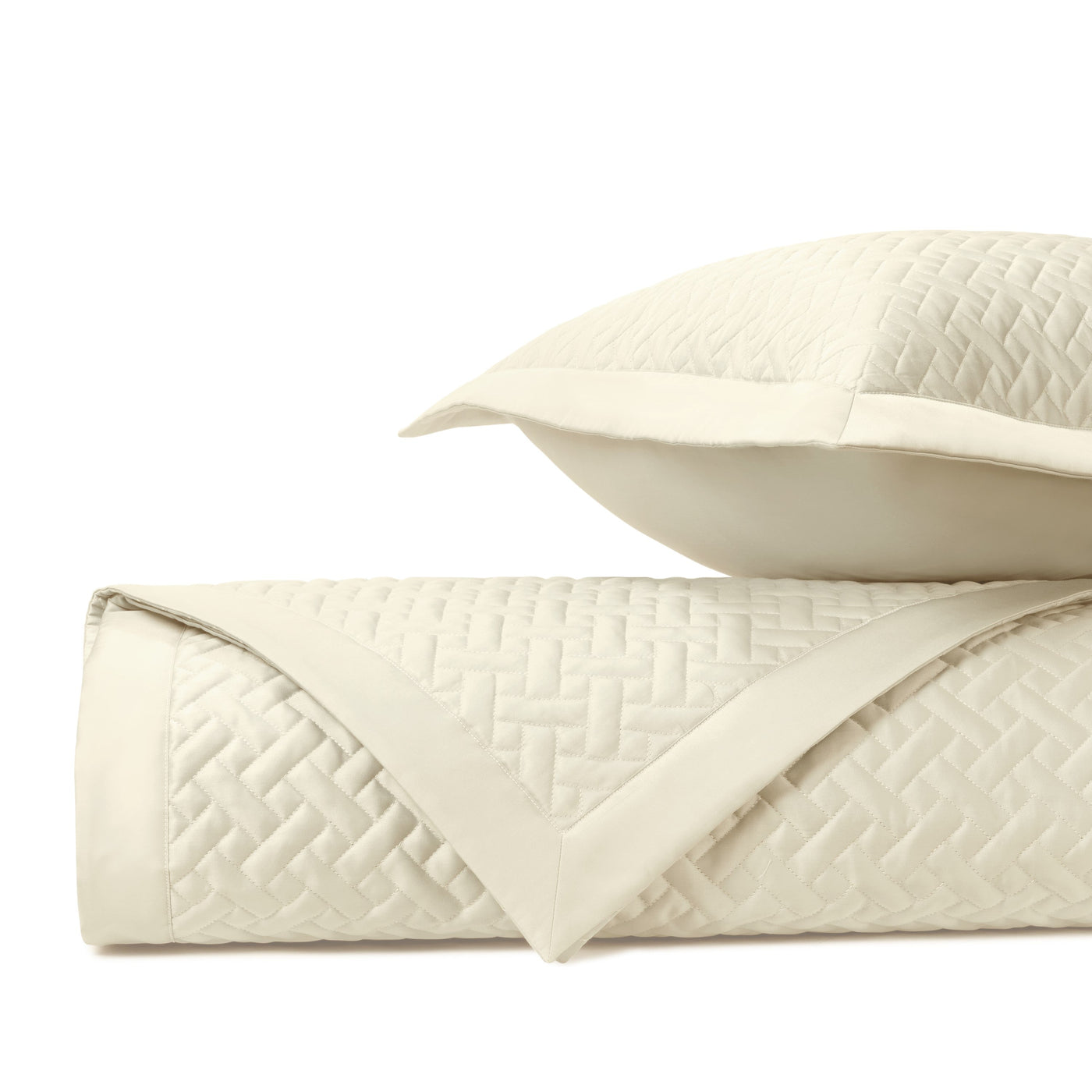 Close-up of ivory quilted basketweave texture on folded coverlet and sham.