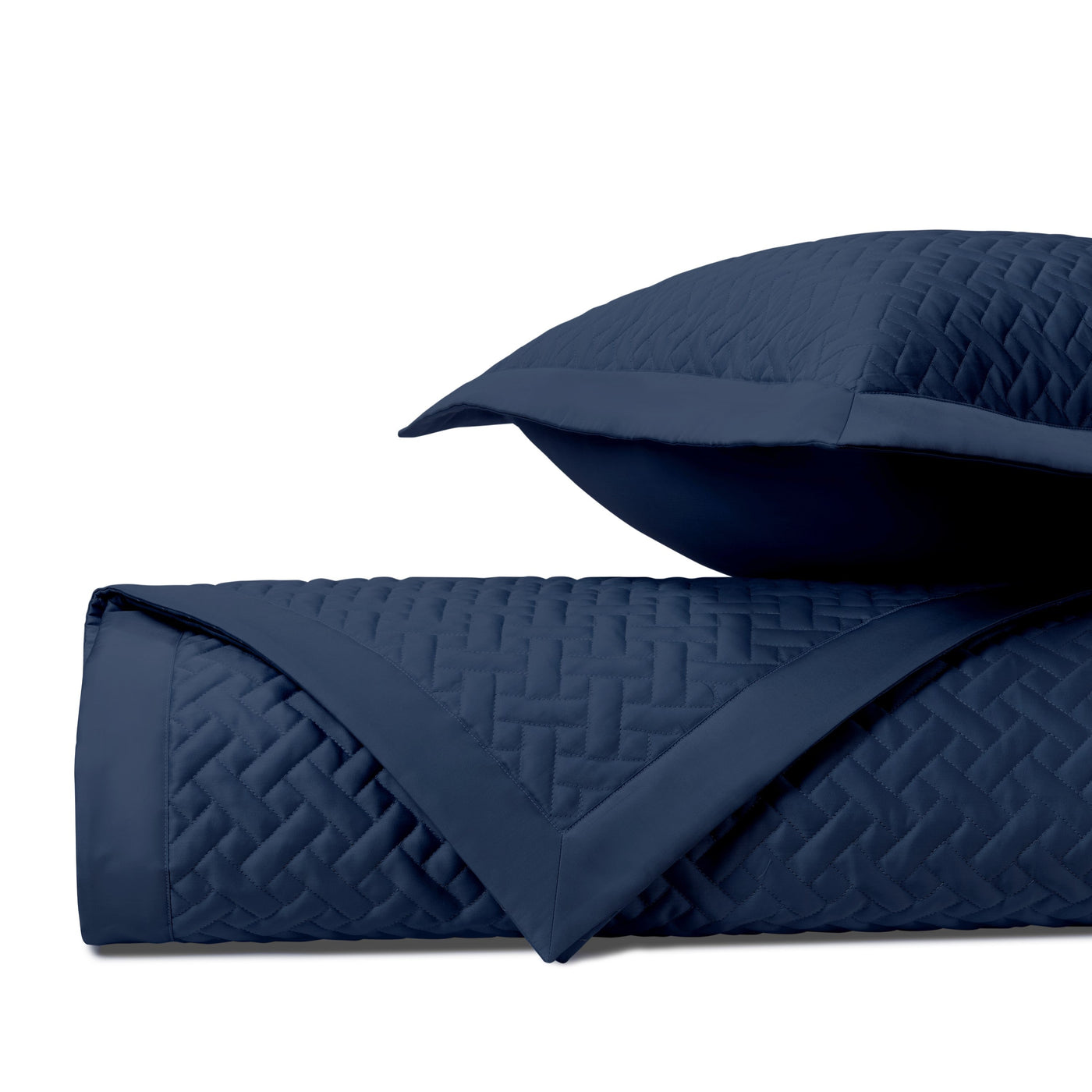 Close-up of navy blue quilted basketweave texture on folded coverlet and sham.