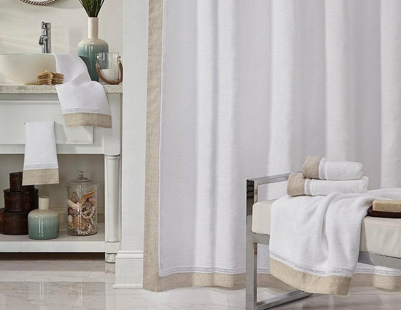 White and linen-bordered Linea towels and shower curtain styled in a neutral bathroom.