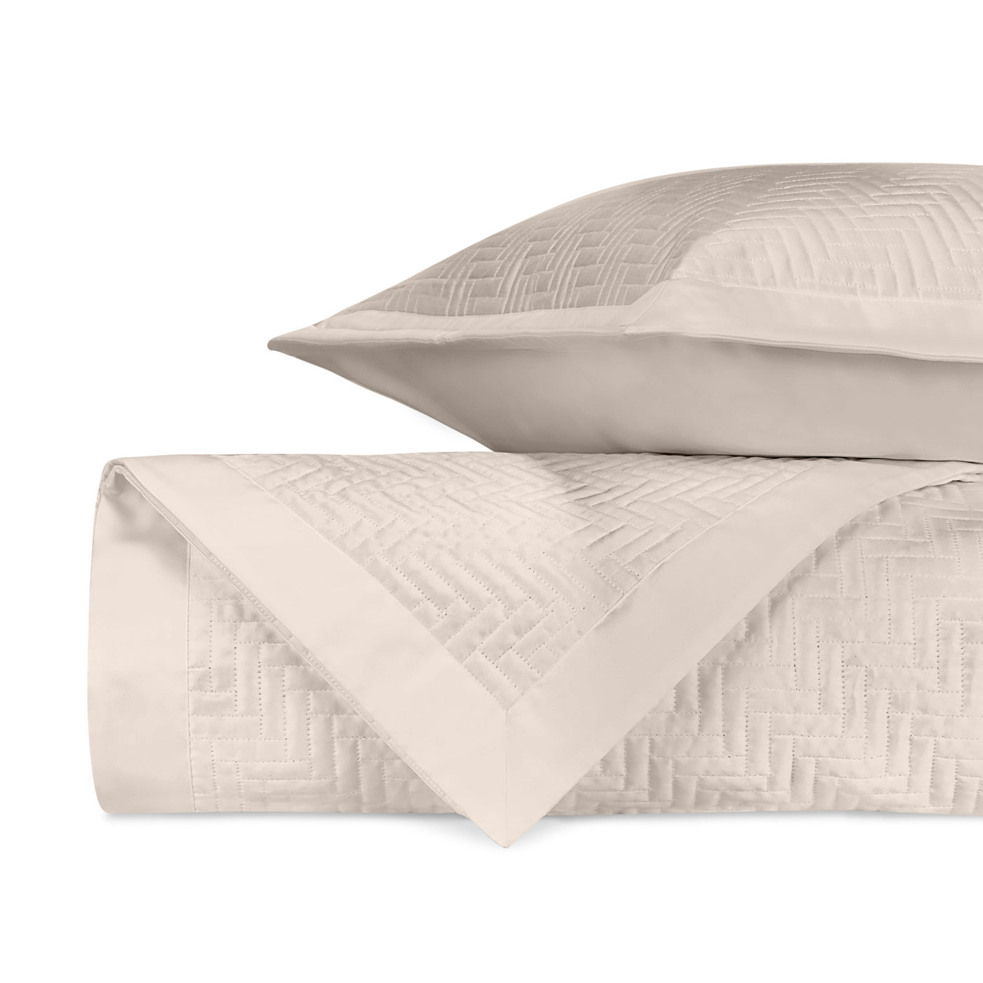 Close-up of ivory quilted herringbone texture on folded coverlet and sham.