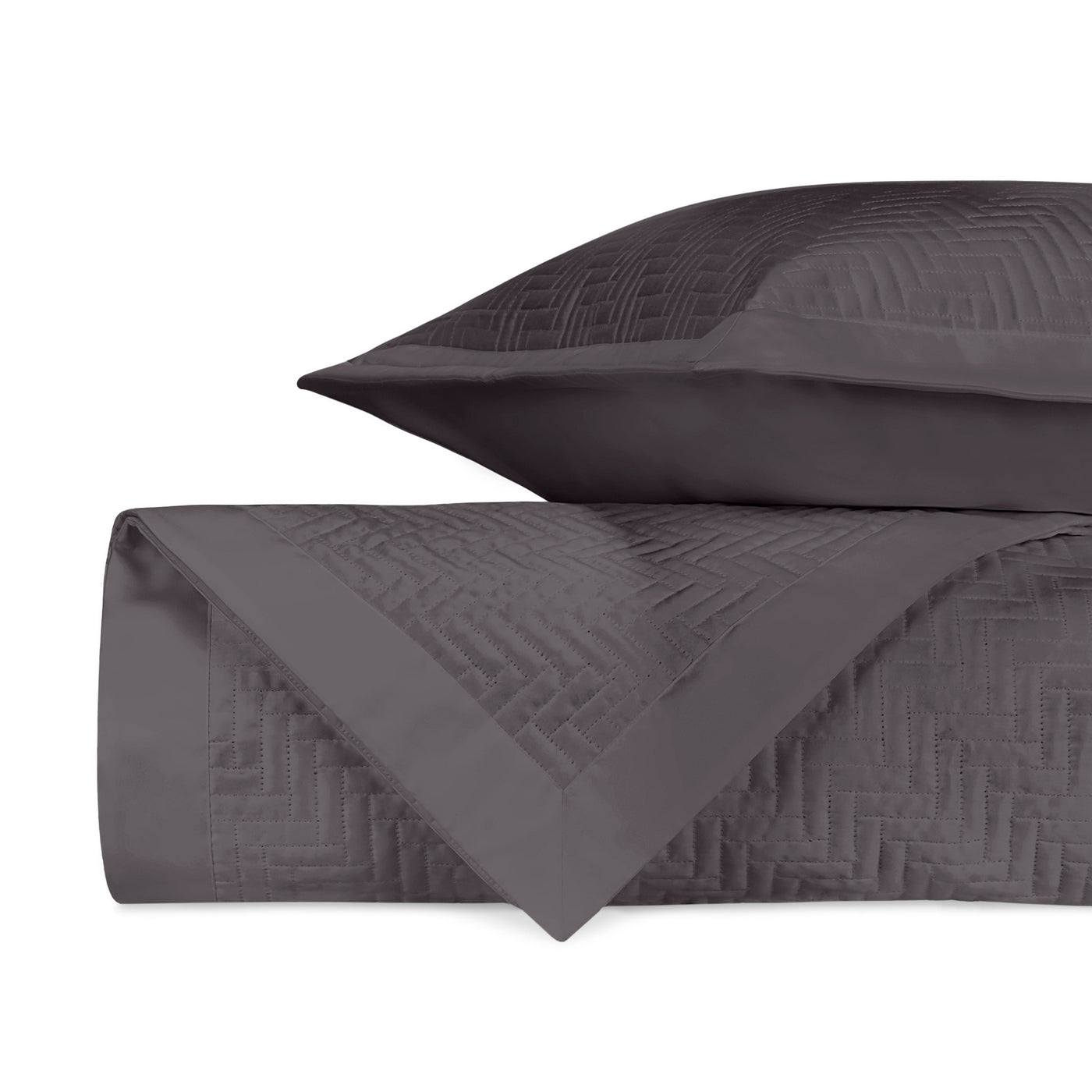 Close-up of charcoal quilted geometric pattern on folded Baxter coverlet and sham.