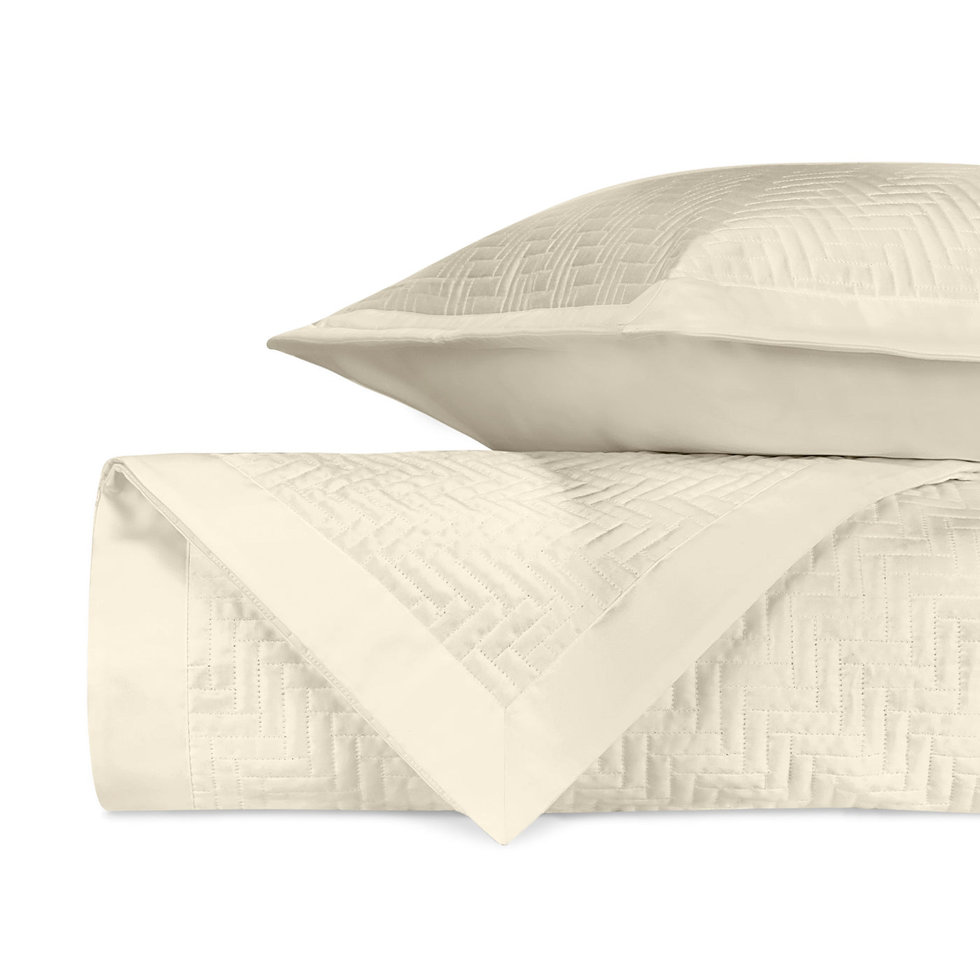 Close-up of ivory quilted herringbone texture on folded coverlet and sham.