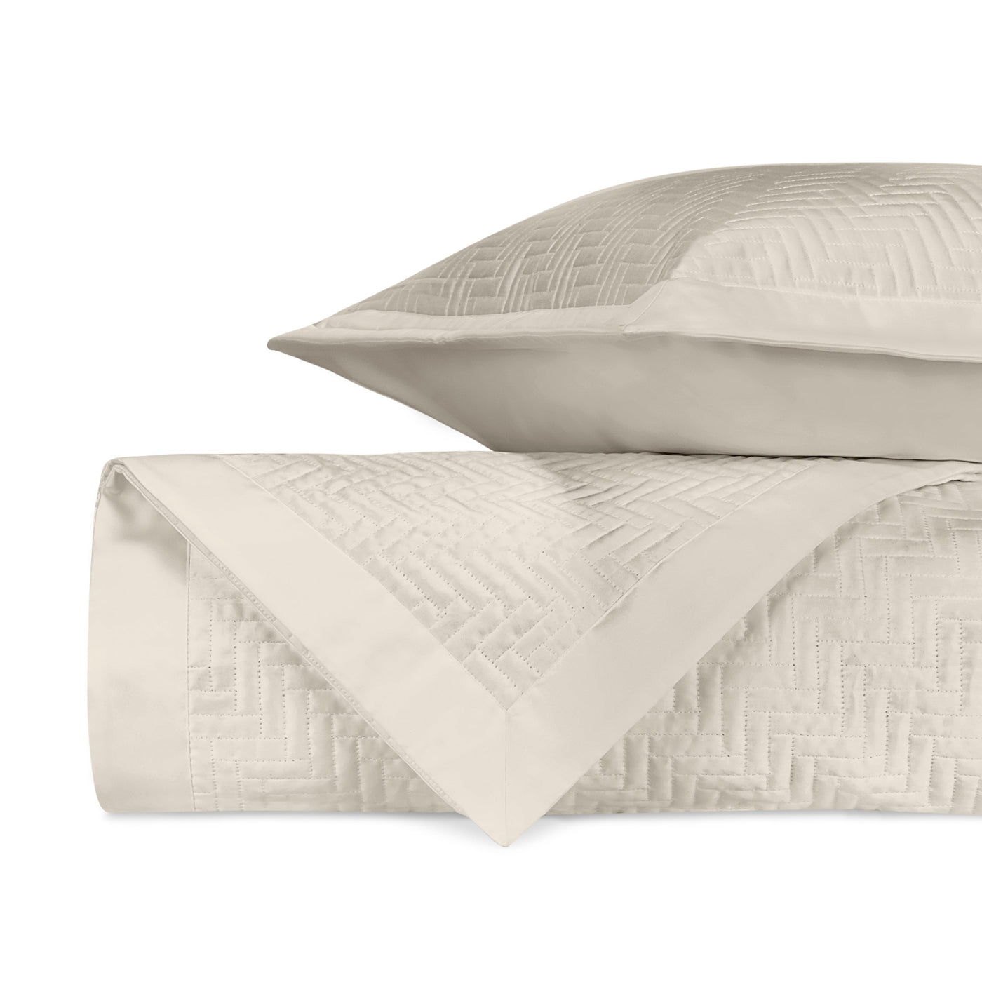 Close-up of ivory quilted herringbone texture on folded coverlet and sham.