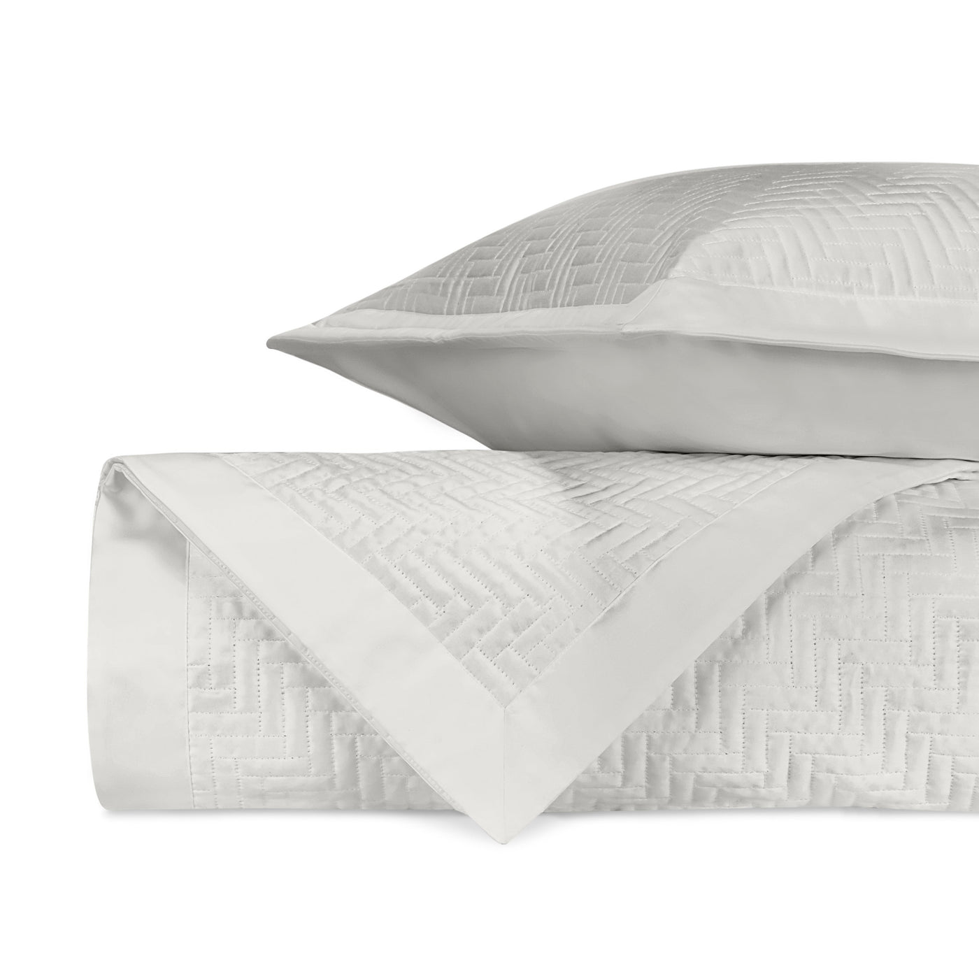 Close-up of white quilted herringbone-pattern coverlet and sham folded together.