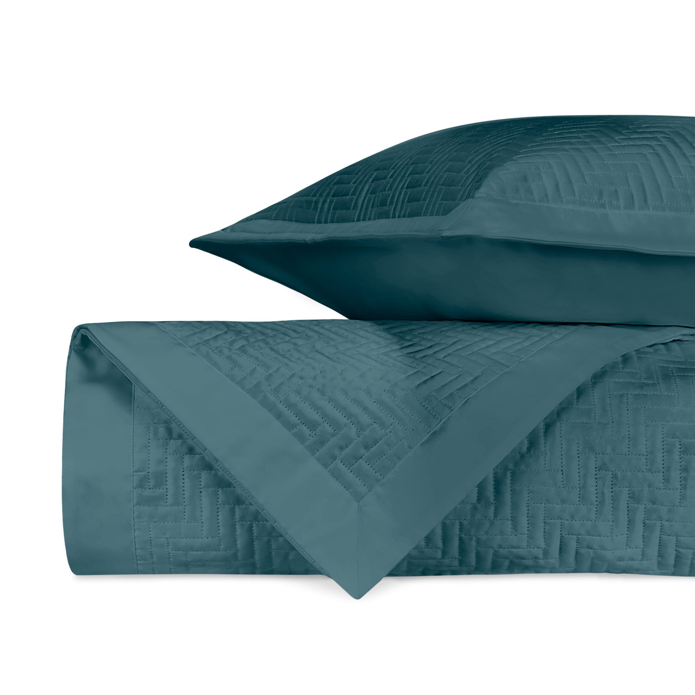 Close-up of teal quilted coverlet and sham showing geometric basketweave stitching detail.