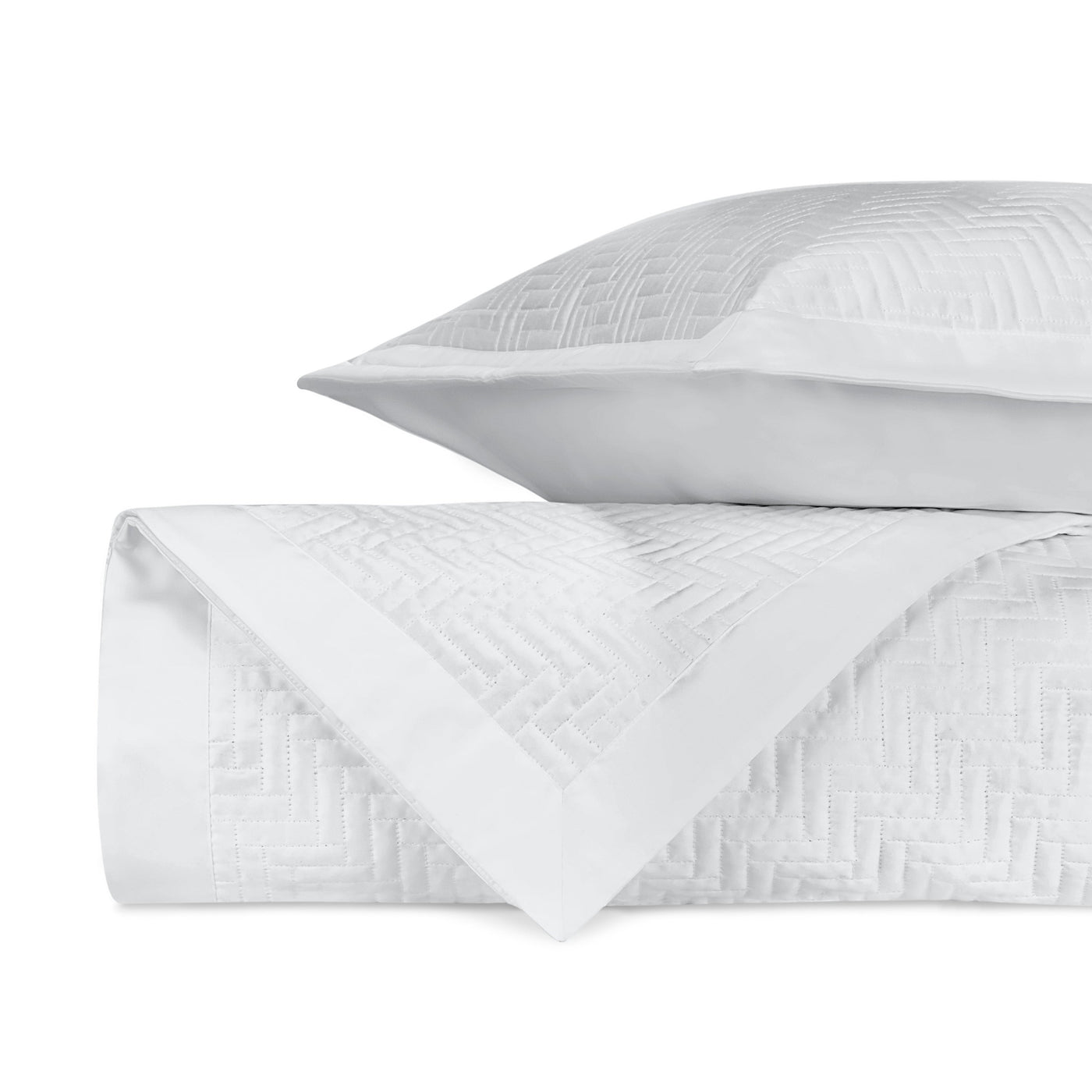 White quilted coverlet and pillow sham with tonal herringbone geometric pattern.