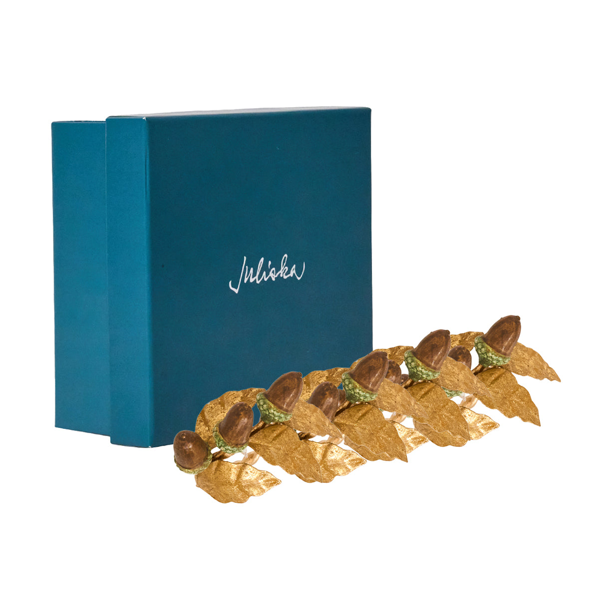 Juliska Forest Walk acorn napkin rings lined up in front of a teal gift box