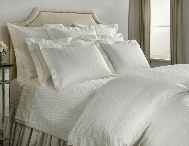 Close-up of ivory Home Treasures Plush 1000 Stripe bedding styled on a fully dressed bed.