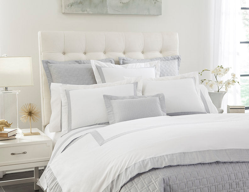 Ivory and dove grey bedroom styled with layered Home Treasures bedding and accent pillows.