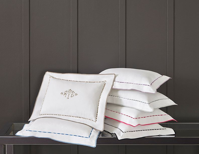 White pillow shams with colorful embroidered trim borders displayed in stacked arrangement.