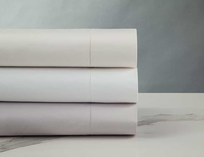 Three folded Home Treasures N°45 Classico yardage pieces in ivory, white, and dove grey.