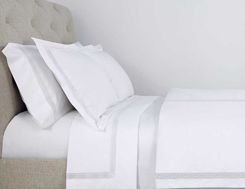 Close-up of Valencia white bedding with silver geometric embroidered border trim.