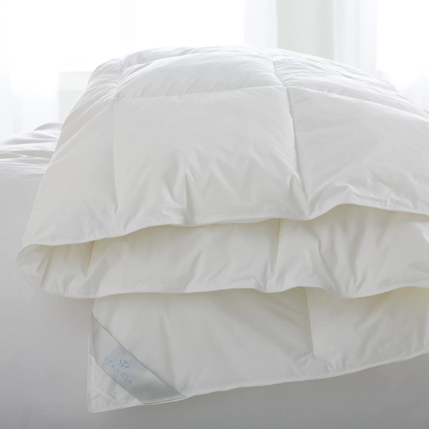 Scandia Home Bergen down-free duvet in white with baffle box stitching, folded on a bed.