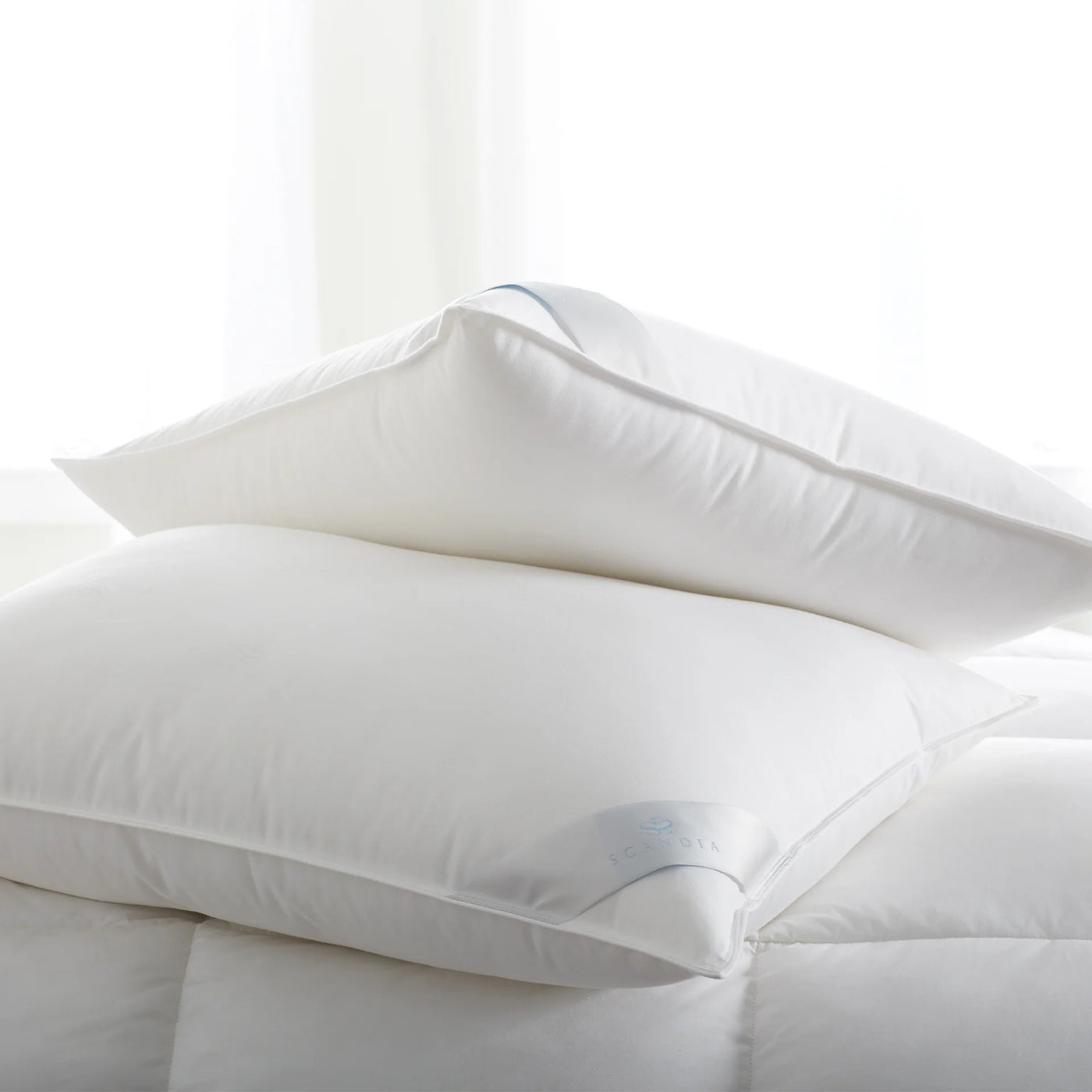 Scandia Home Bergen white down-free pillow stacked on ivory duvet in soft natural light.