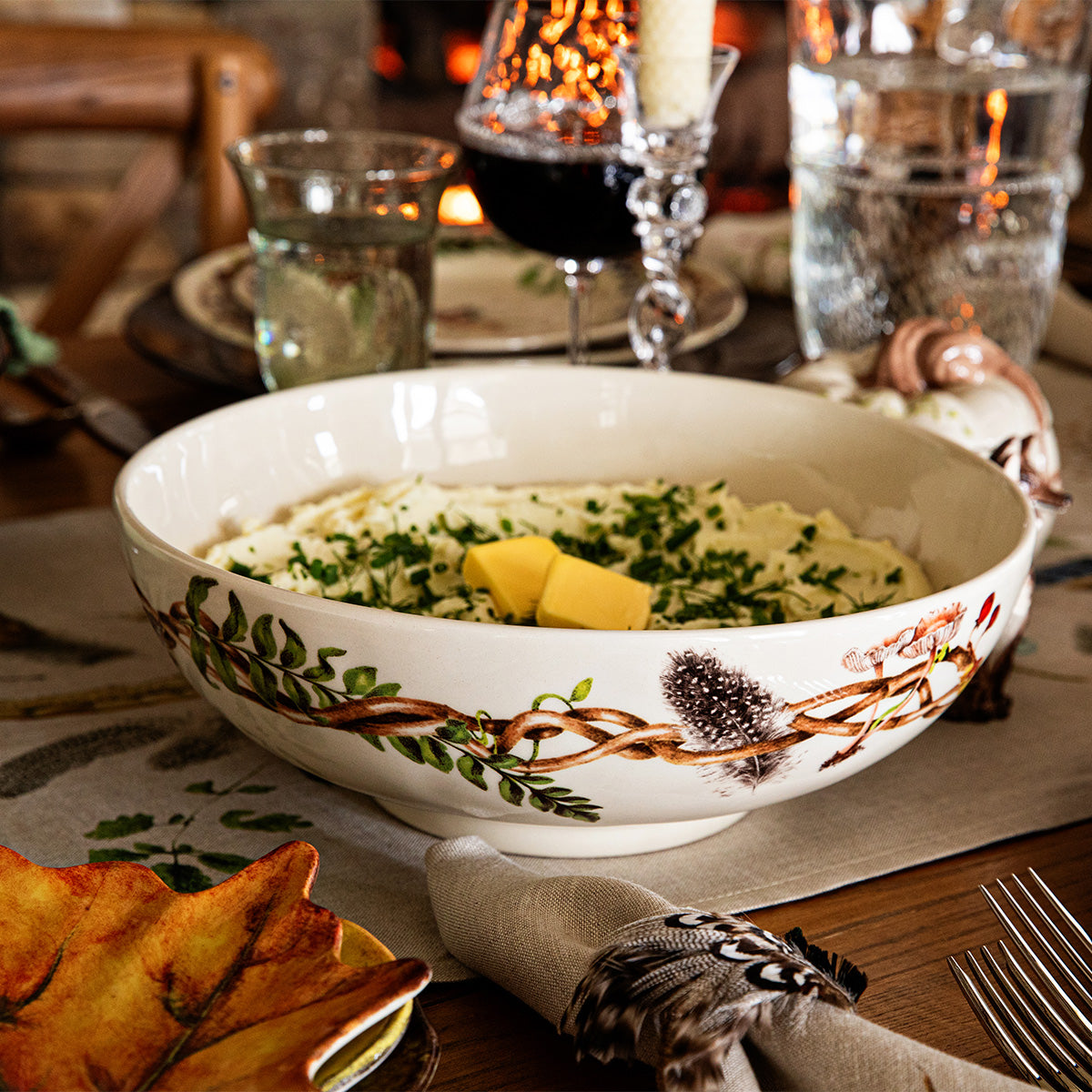 Forest Walk 12 inch serving bowl filled with a potato dish on a table with glasses and napkin rings