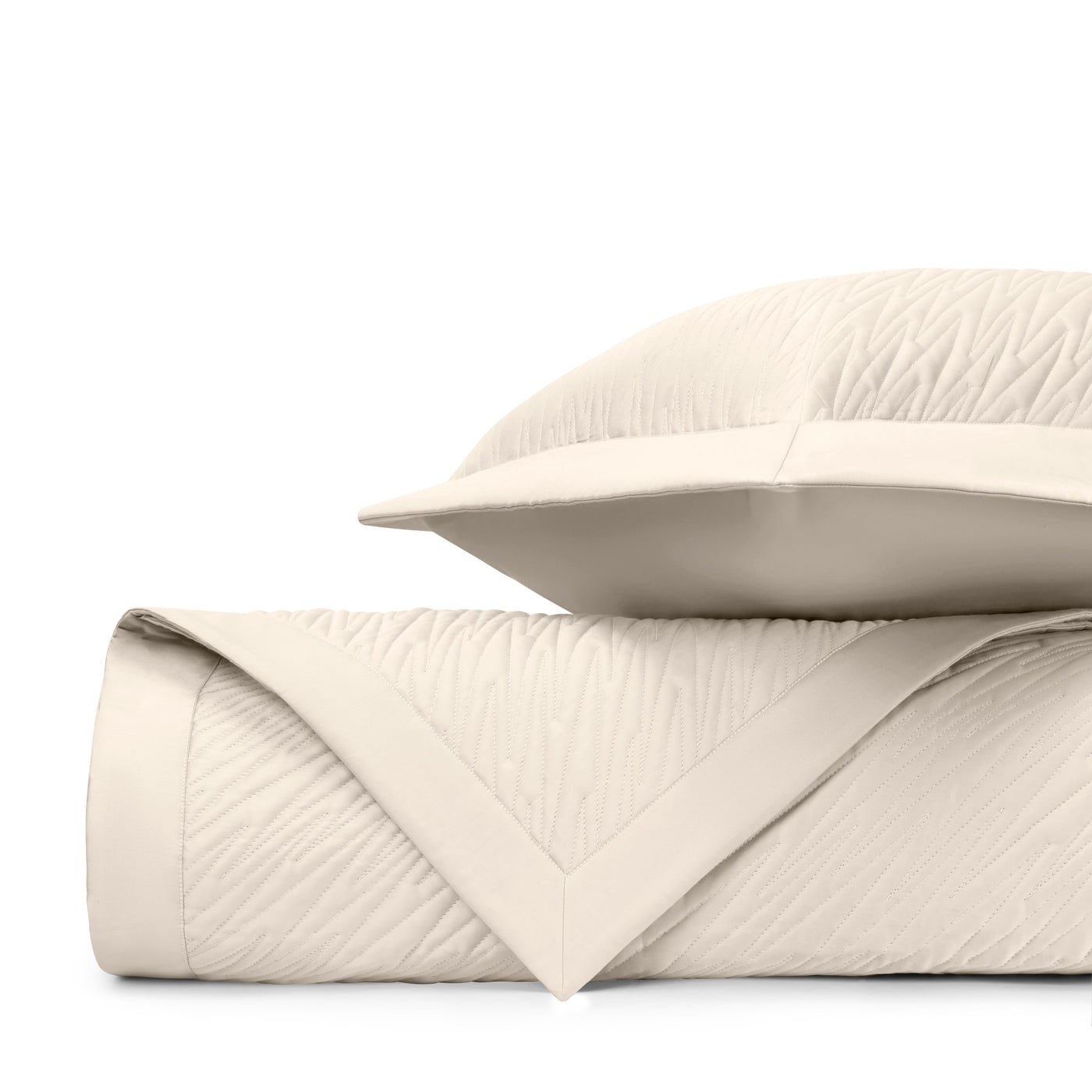 Close-up of ivory quilted fabric with subtle wave-textured stitching and mitered border detail.