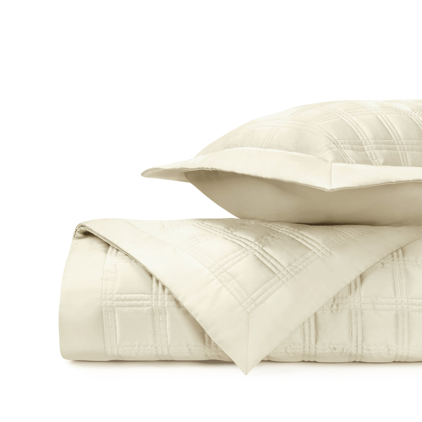 Close-up of ivory quilted cotton with geometric block stitching pattern.