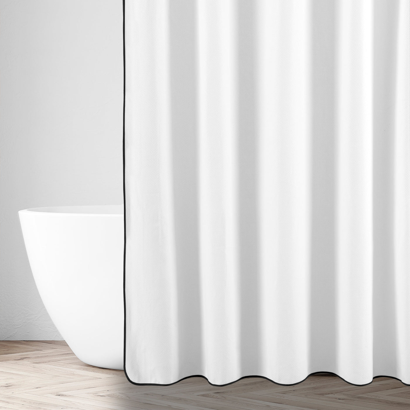 White cotton shower curtain with black border trim, styled in a minimal bathroom setting.