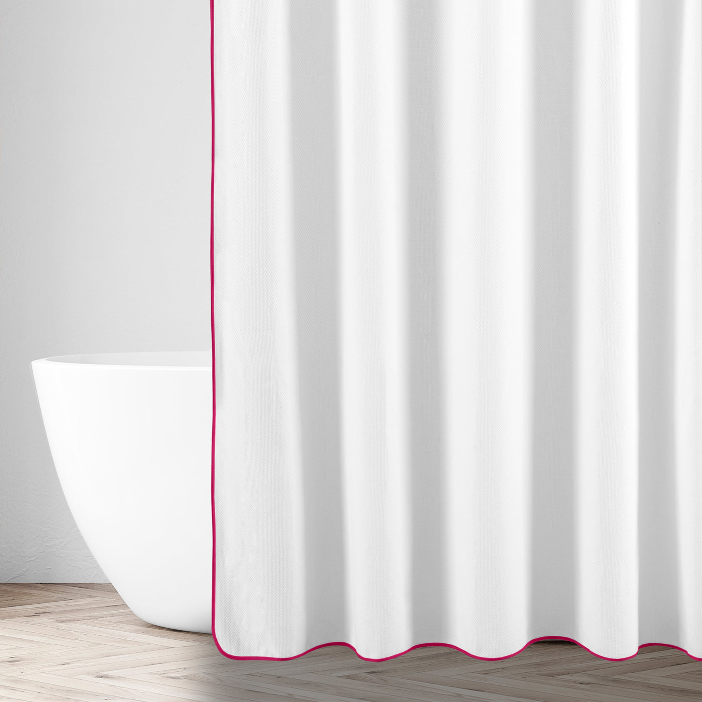 White shower curtain with fuchsia trim edge, styled in a bright bathroom with freestanding tub.