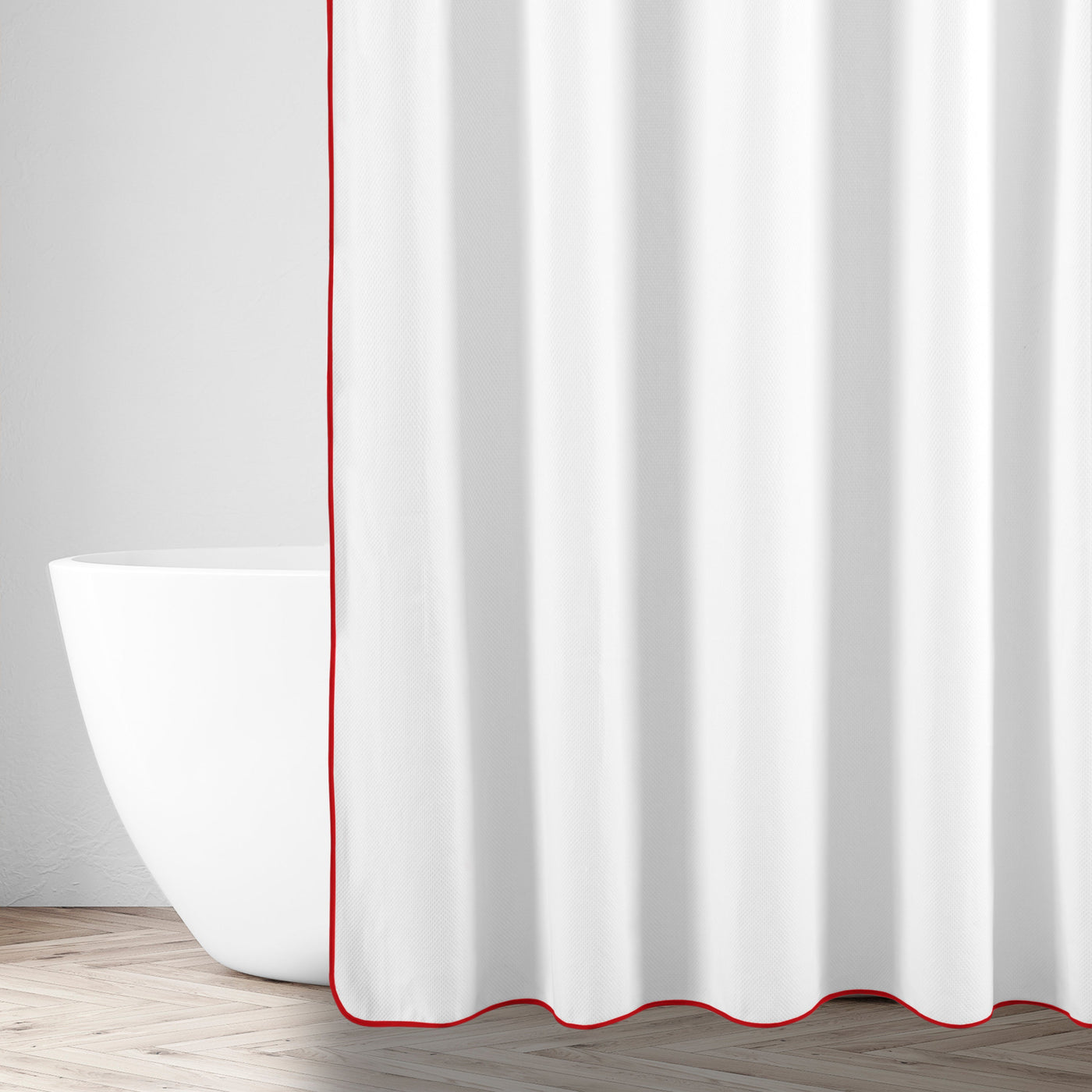 Red-trimmed edge detail on white linen shower curtain beside a freestanding tub.