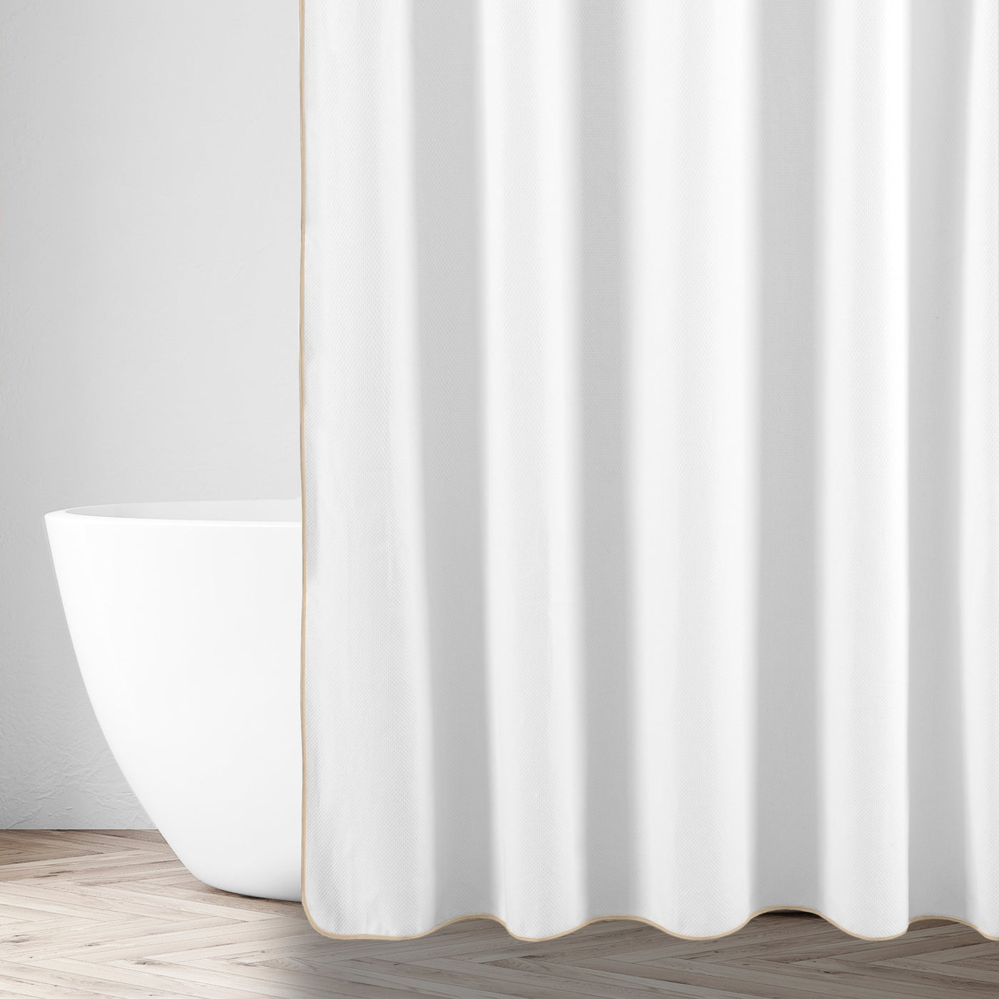 White linen shower curtain with champagne trim, styled beside a freestanding bathtub.