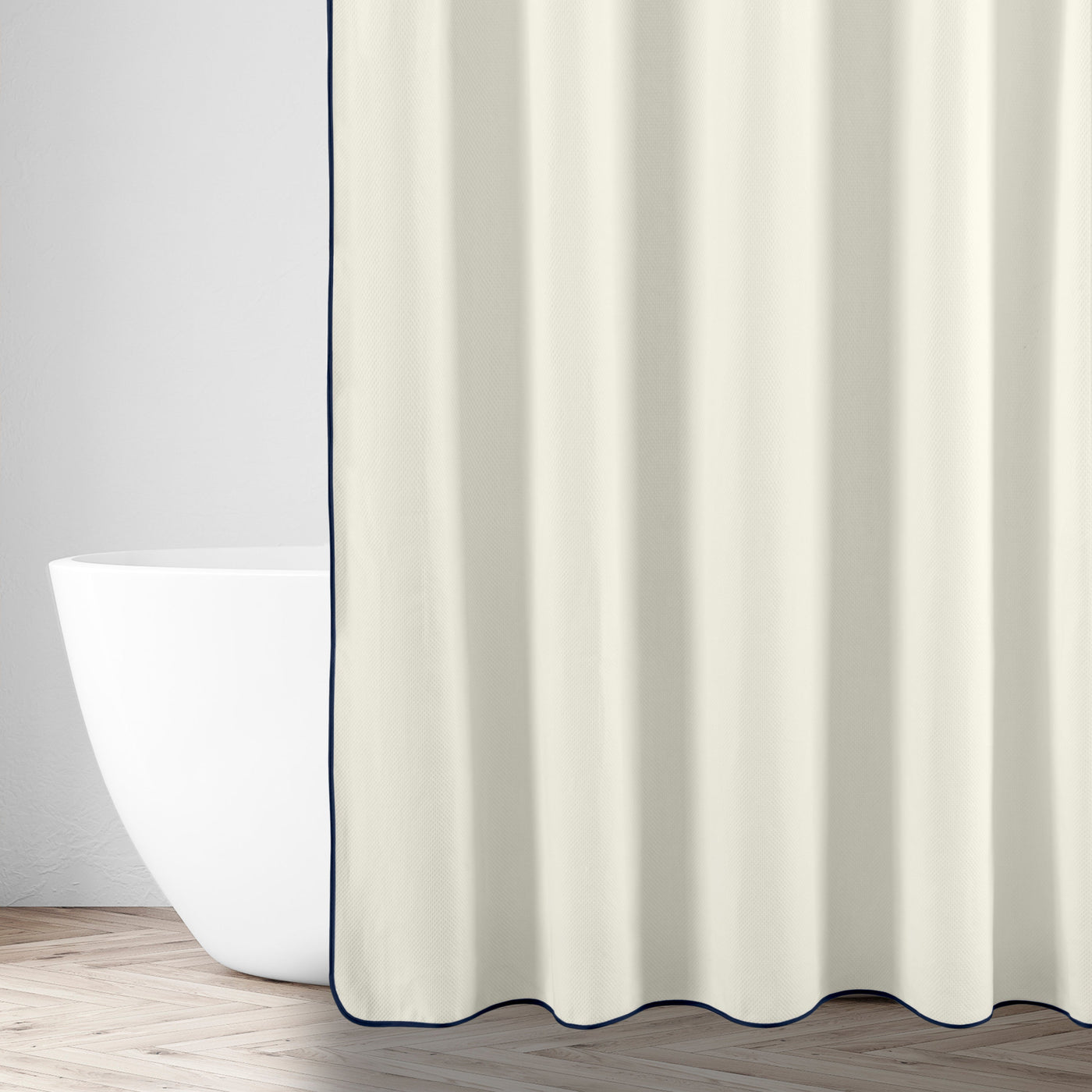 Ivory shower curtain with navy border trim, styled beside a freestanding bathtub.