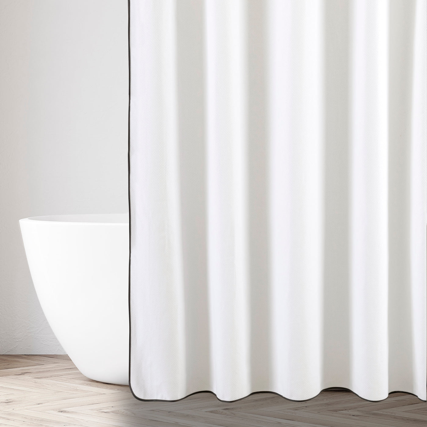 Ivory shower curtain with charcoal border trim, styled beside a freestanding white bathtub.