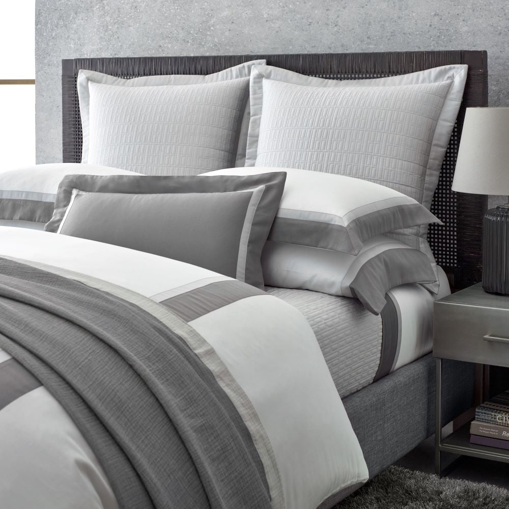 Styled bed with dove grey and pearl white bordered duvet cover and textured euro shams.