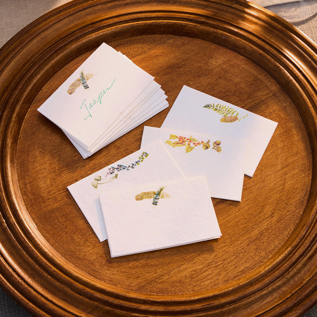 Forest Walk assorted place cards scattered on a round wooden tray
