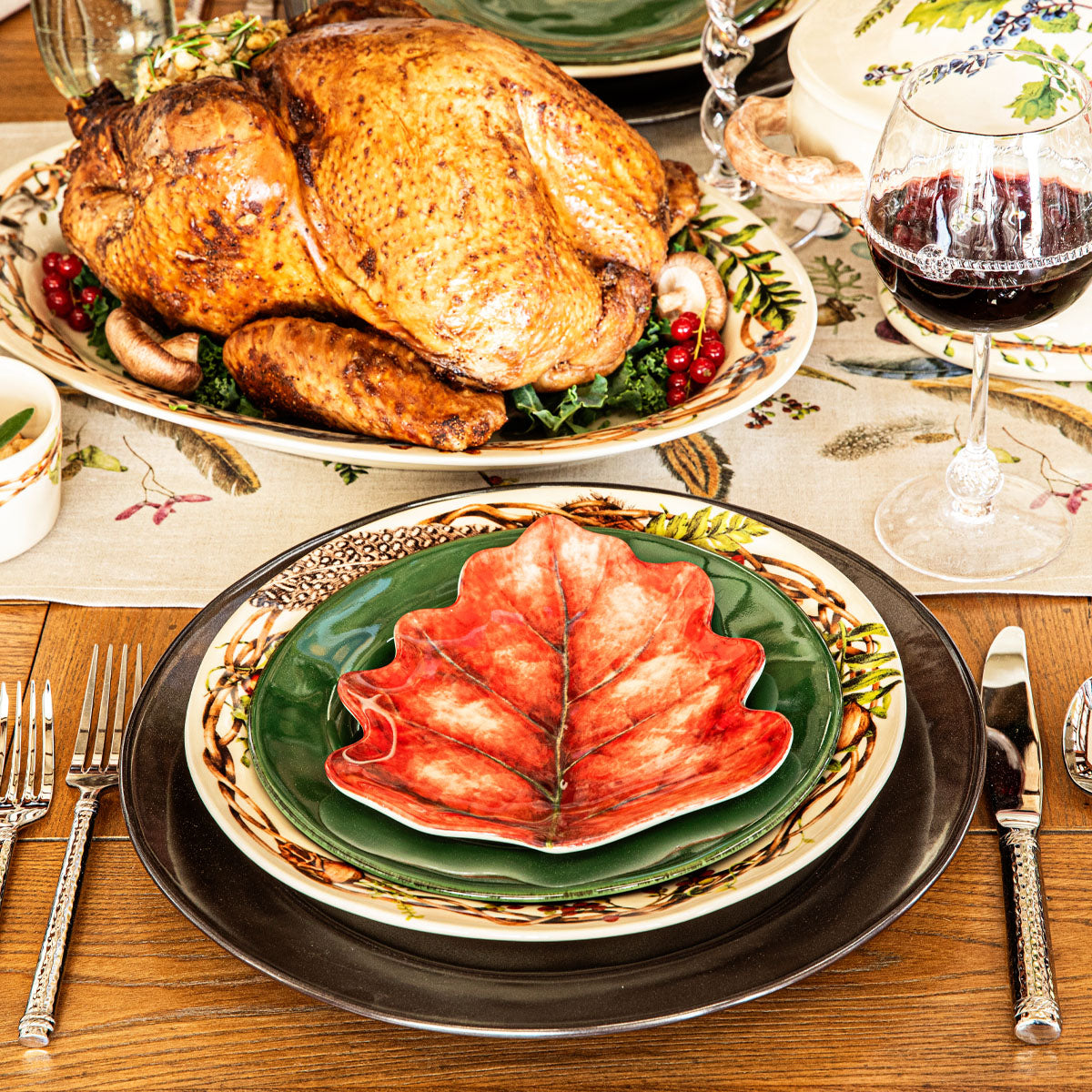 Red Forest Walk leaf plate on a place setting with a roast turkey and red wine behind