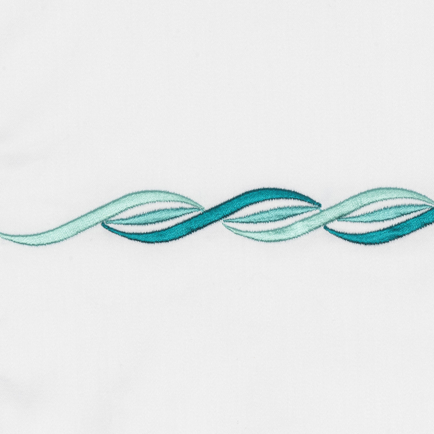 Close-up of teal and aqua embroidered wave motif on white cotton.