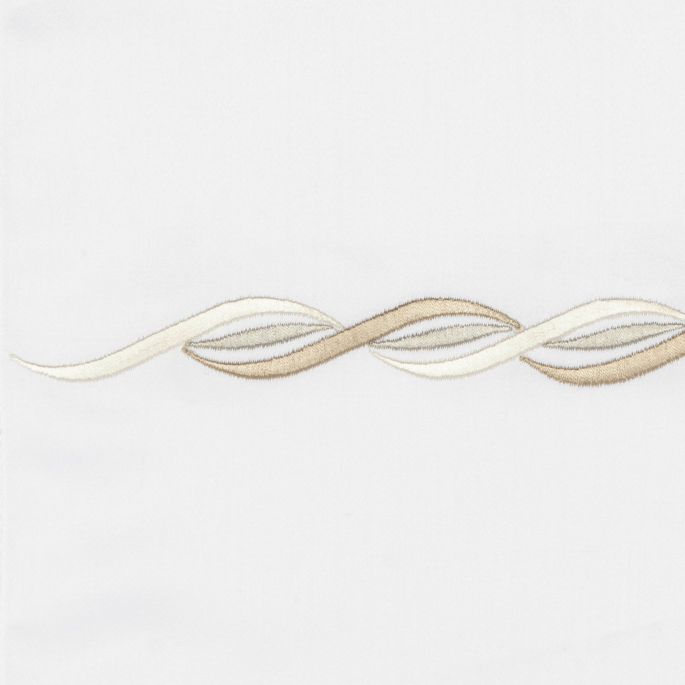 Close-up of ivory and champagne leaf embroidery on white linen fabric.