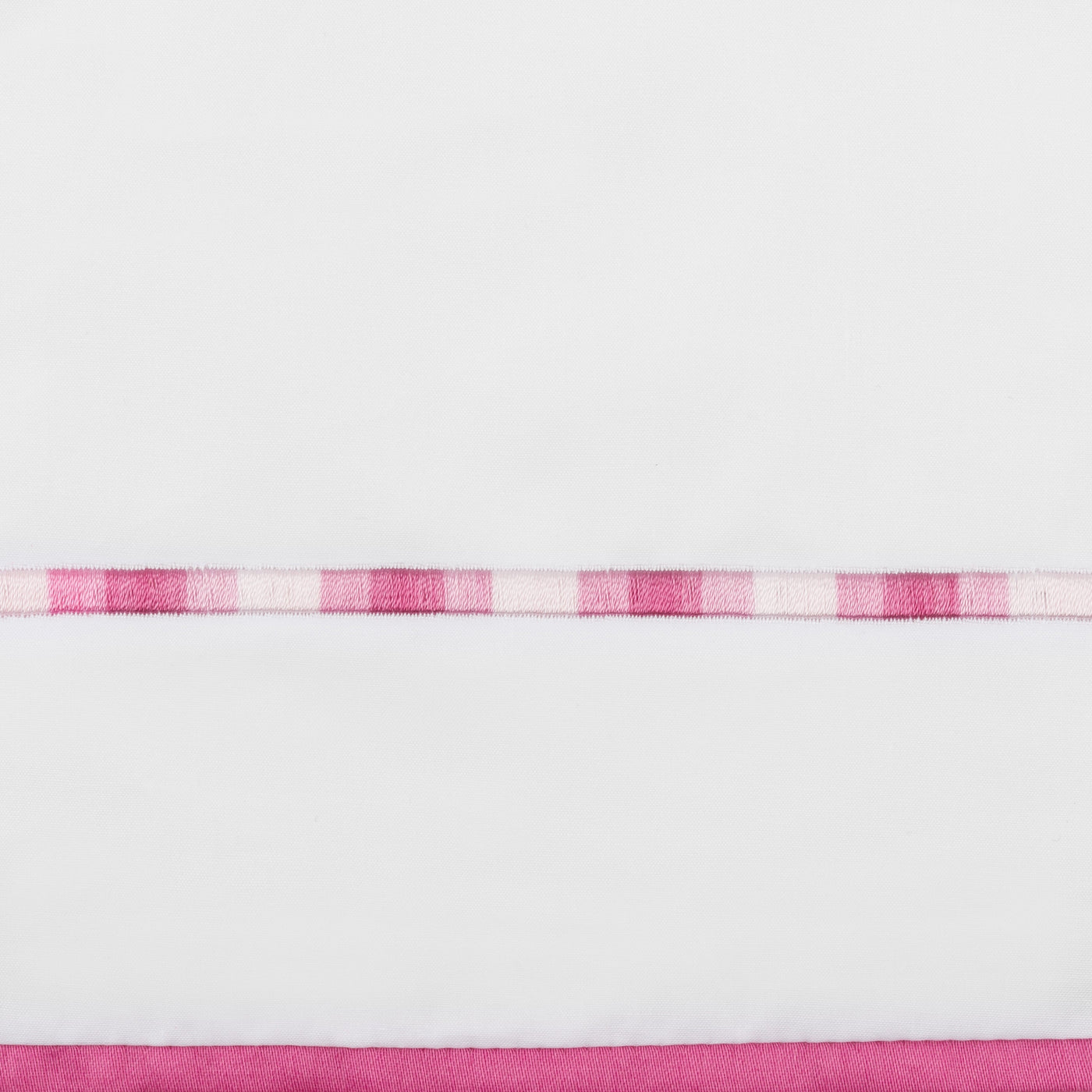 Close-up of raspberry and blush checkered ribbon trim on white linen flat sheet.