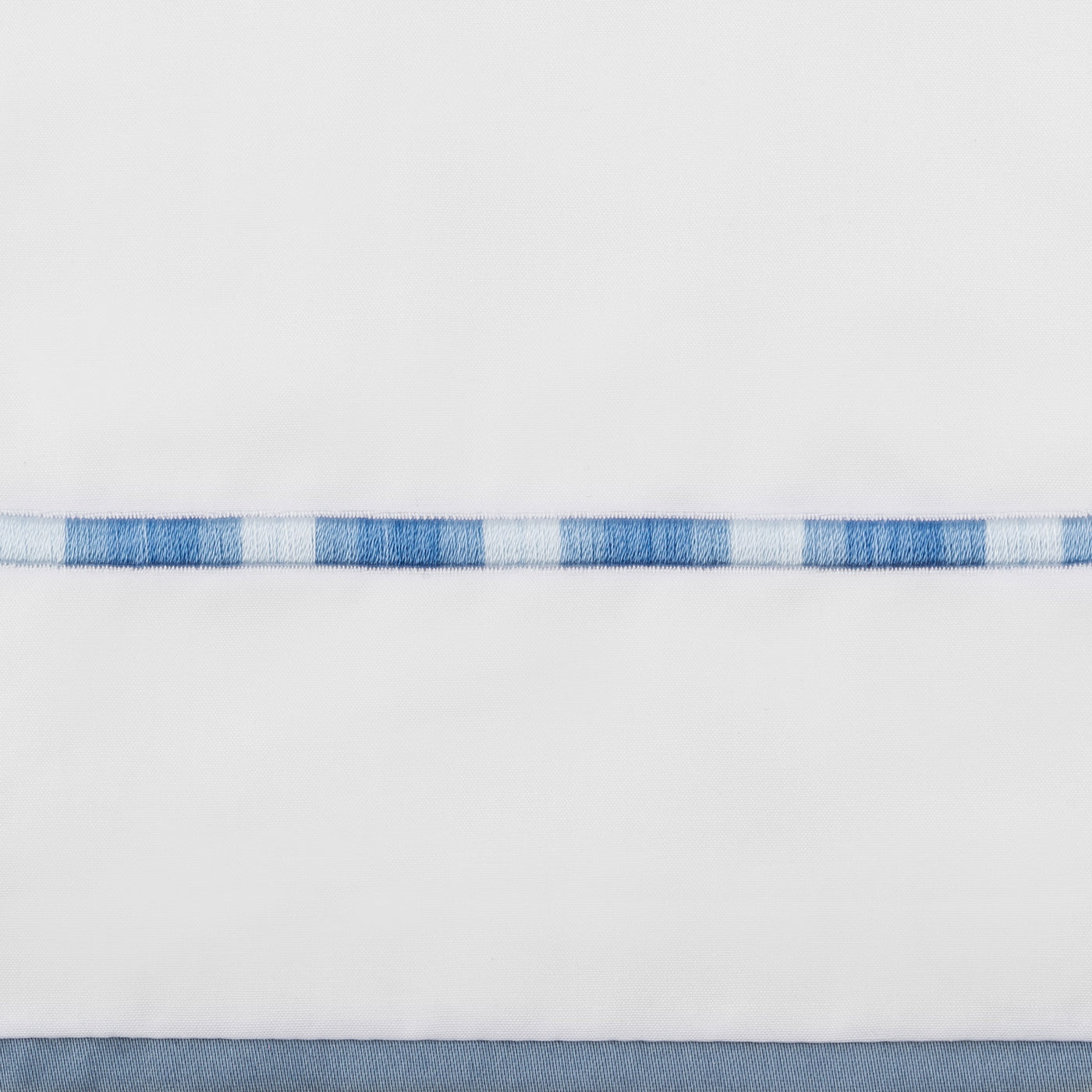 Close-up of blue and white woven check border trim on a white flat sheet.