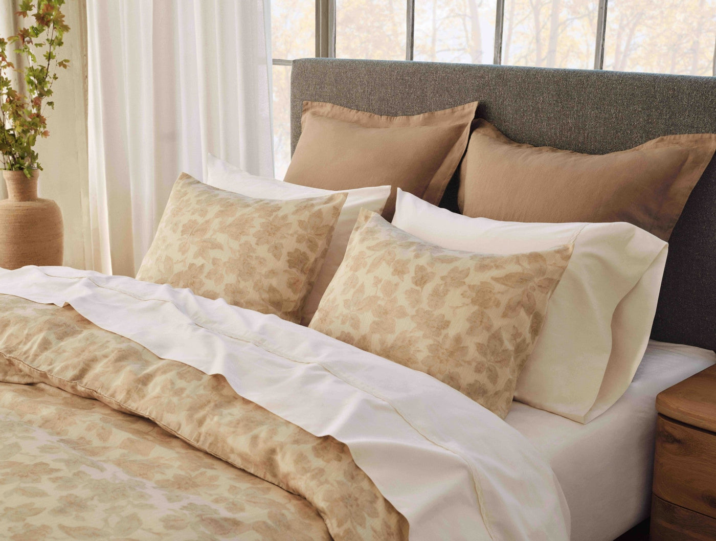 Camellia Print duvet cover in warm golden tones styled on a bed with white sheets.