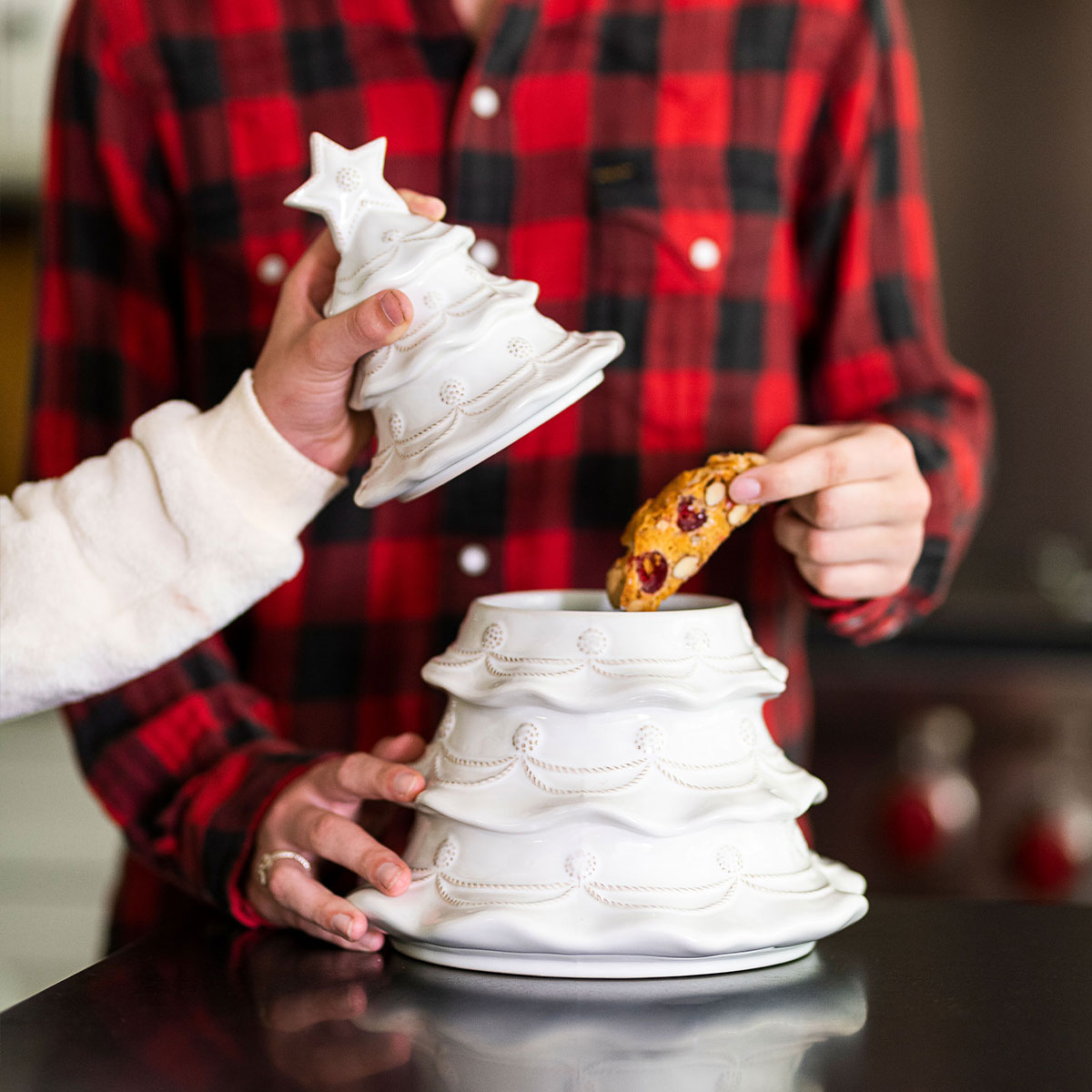 Child in a plaid shirt reaching into a whitewash Christmas tree cookie jar