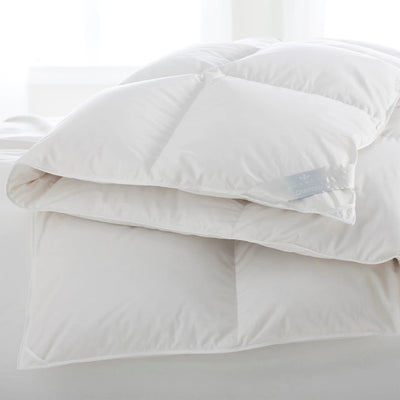 Scandia Home Chamonix white down duvet folded on a bed with white linens.