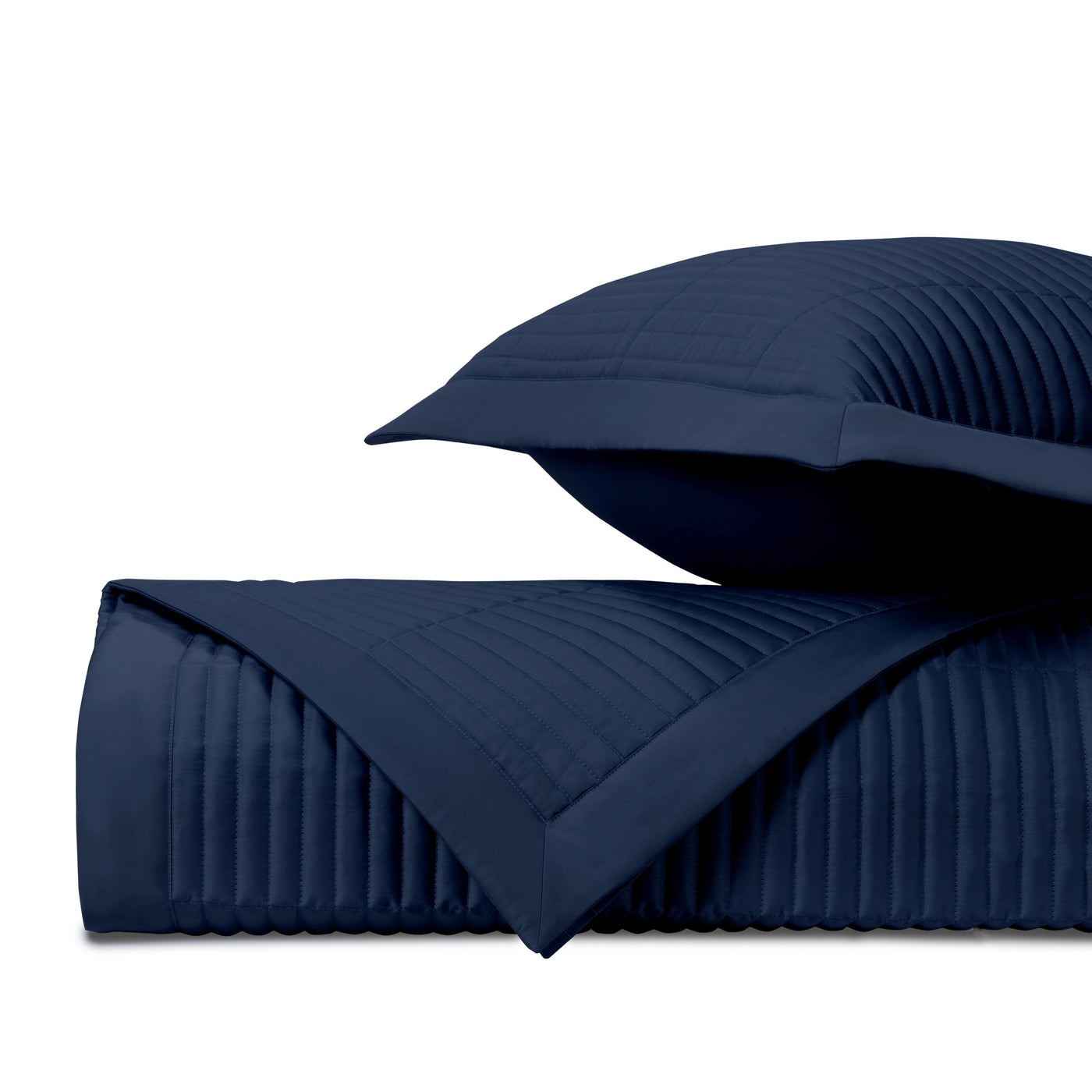 Close-up of navy blue channel-quilted texture on folded coverlet and sham.