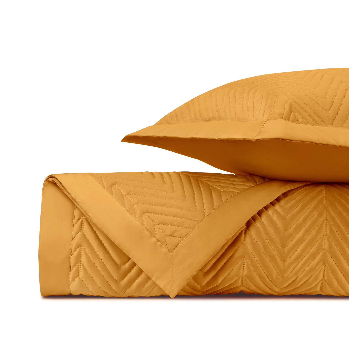 Saffron quilted coverlet and sham folded, showing chevron stitching detail.