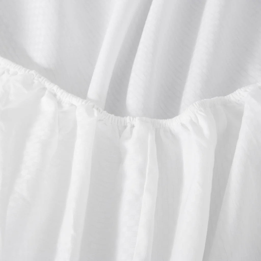 Close-up of Frette's Checkered Sateen Fitted Sheet with a silky texture, soft folds, and visible seams, evoking the elegance of a boutique hotel bed.