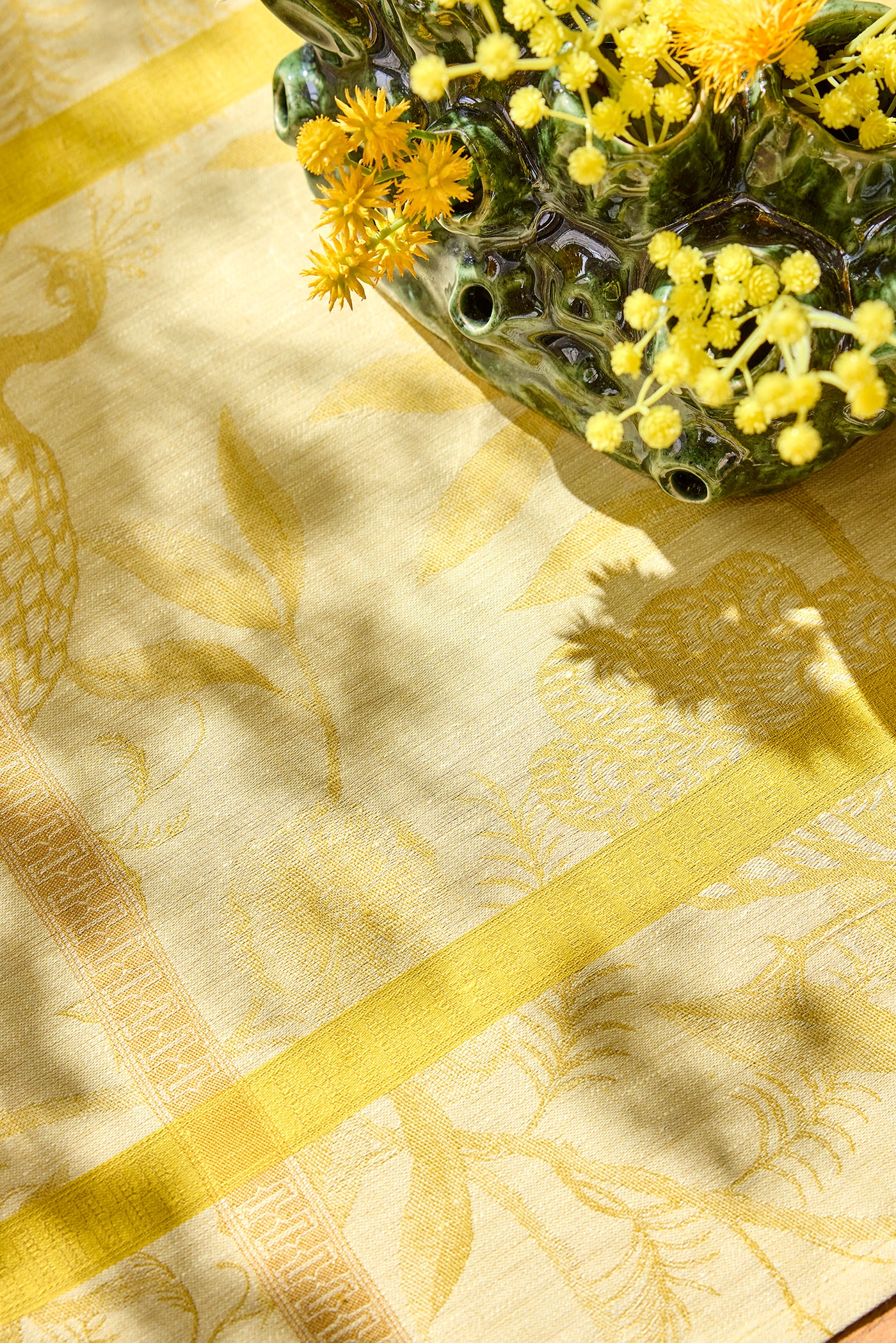 Close-up of citrine jacquard weave with botanical motif and chartreuse border stripe.