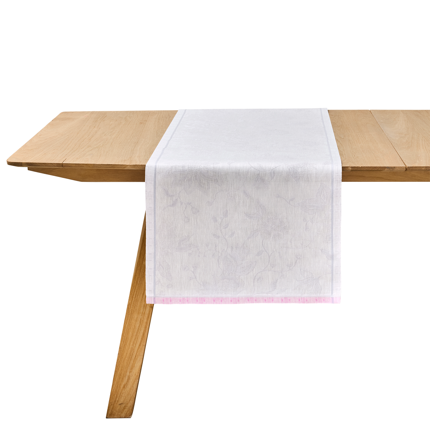 White jacquard table runner with blush border draped over a natural wood table.