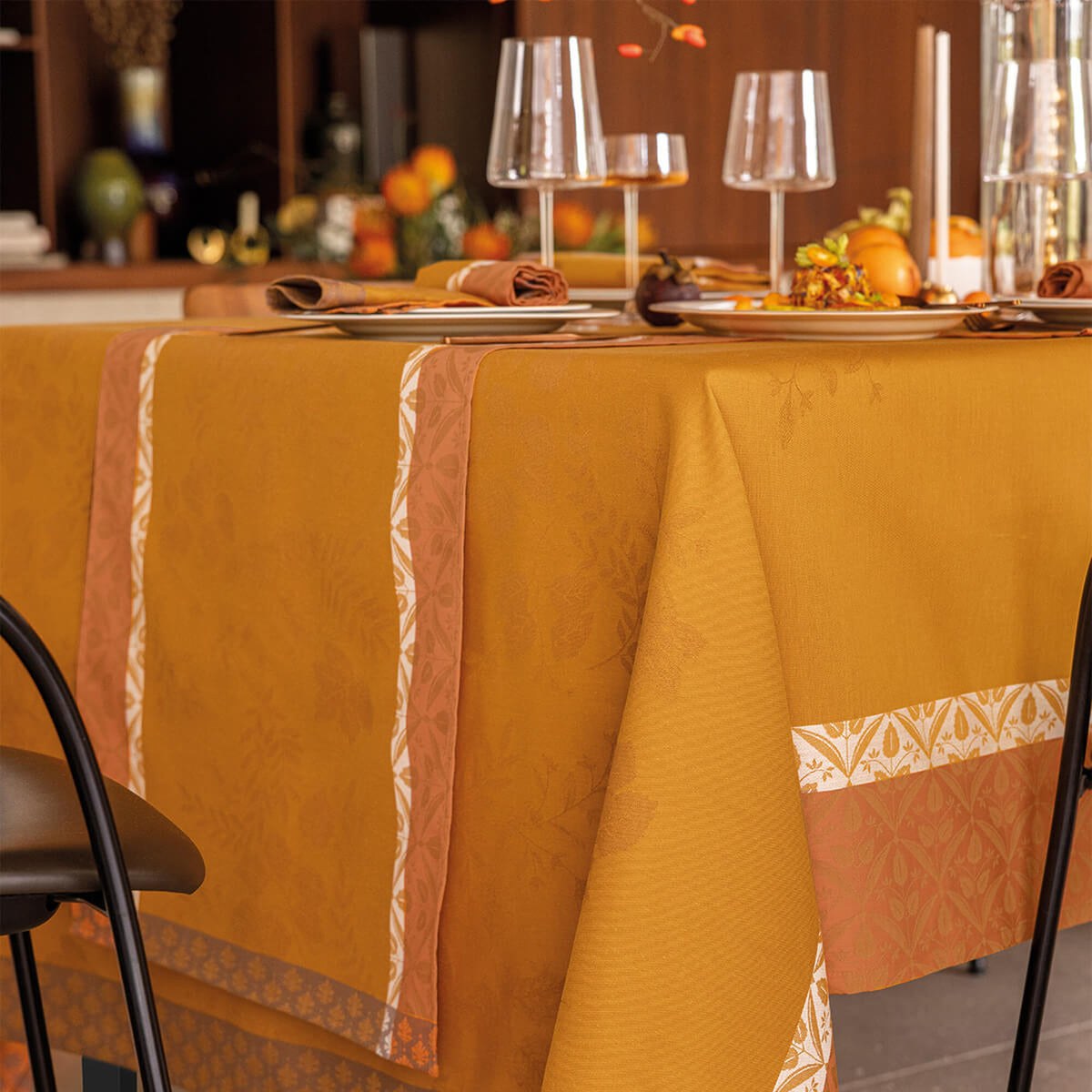 Orange Manor Lane table runner layered on matching tablecloth, autumn table setting.