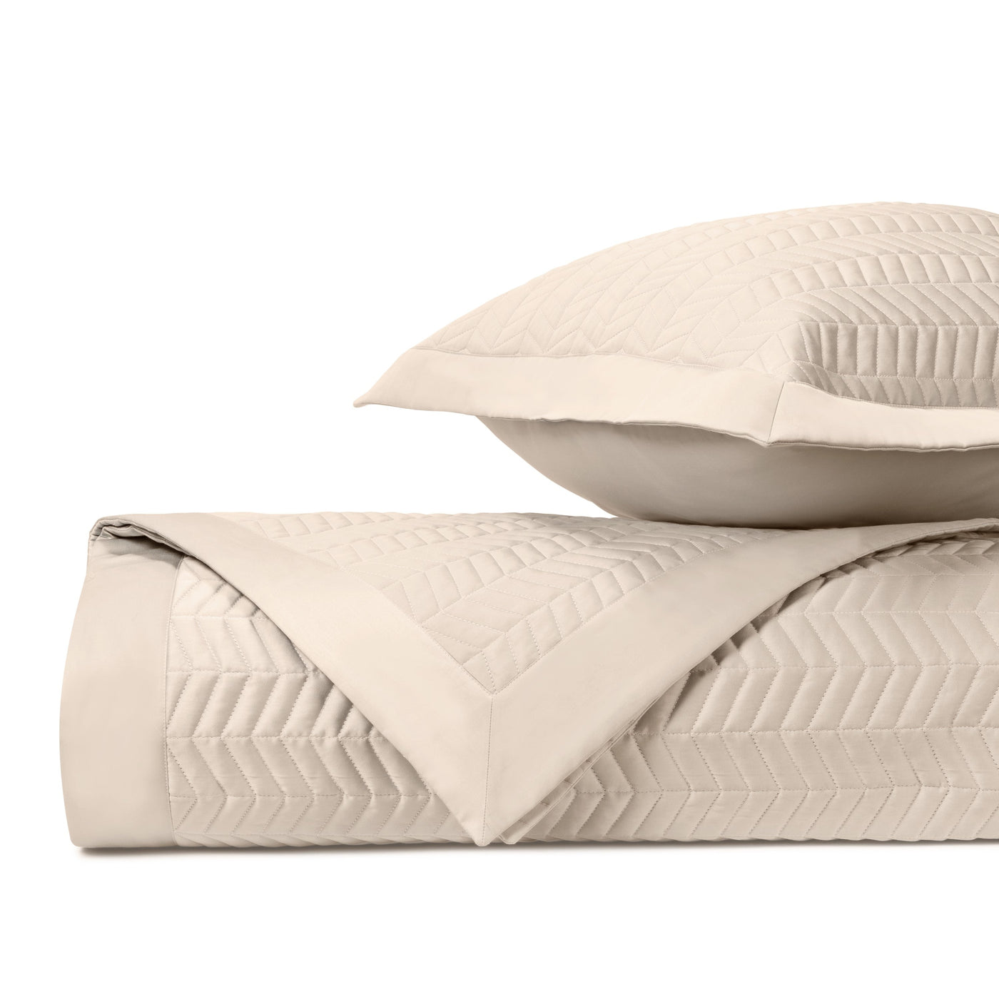 Close-up of ivory quilted fabric with chevron stitching pattern and bordered edge.